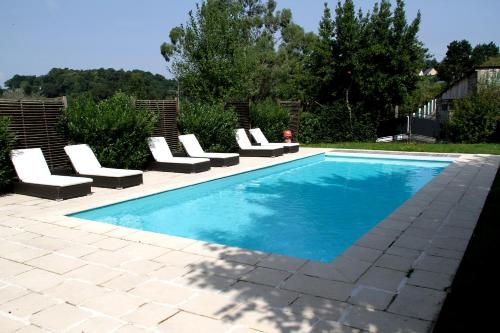 a swimming pool with white lounge chairs and a pool at Hotel De La Poste in Mortain