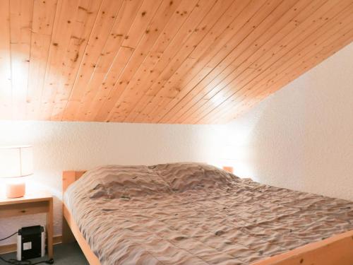 a bed in a room with a wooden ceiling at Résidence Asphodeles in Méribel