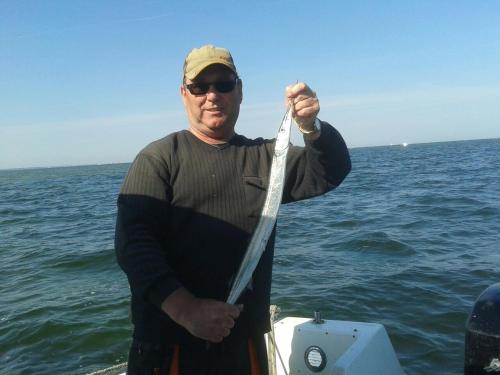 a man standing on a boat holding a fishing pole at Halbinsel Resort Peenemünde in Peenemünde
