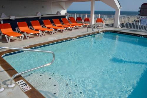 a pool with chairs and umbrellas in it at Monte Carlo Boardwalk / Oceanfront Ocean City in Ocean City