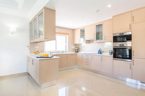 a large kitchen with wooden cabinets and appliances at Lakeside Country Club - Apartamentos Turísticos in Quinta do Lago