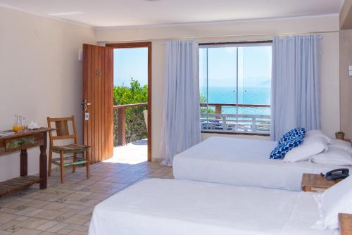a bedroom with two beds and a balcony with the ocean at Pousada La Dolce Vita in Búzios