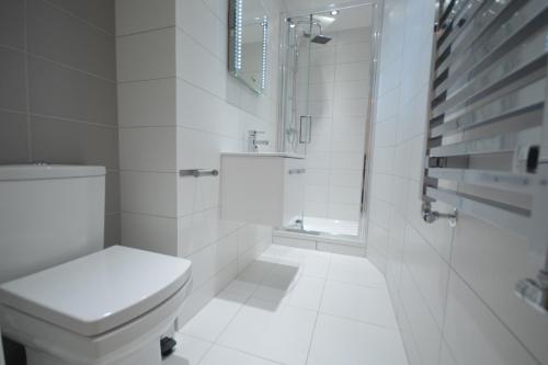 a white bathroom with a toilet and a sink at St Anne's Court by Indigo Flats in London