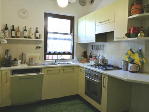 a kitchen with white cabinets and a sink and a window at Villetta nella Pineta Santa Margherita di Pula in Santa Margherita di Pula