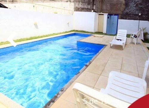 - une piscine avec de l'eau bleue et des chaises blanches dans l'établissement Apartamento 2 Quartos vista mar, à Salvador