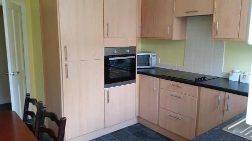 a kitchen with wooden cabinets and a microwave at Central Dumfries in Dumfries