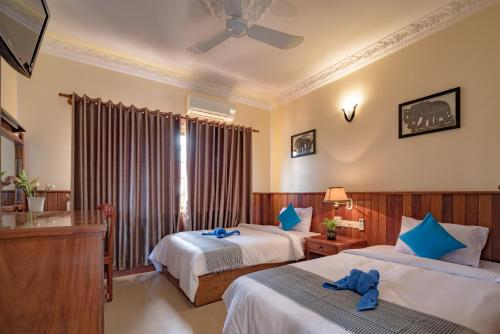 a hotel room with two beds and a window at The Siem Reap Chilled Backpacker in Siem Reap