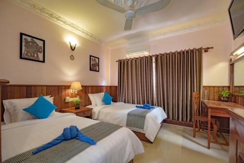 a hotel room with two beds and a desk at The Siem Reap Chilled Backpacker in Siem Reap