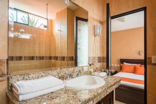 a bathroom with a sink and a bed at Hotel Flamingo in Puerto Ayora