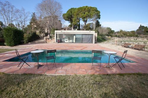 una piscina con 2 mesas y sillas frente a una casa en Mas del Molí en Reus