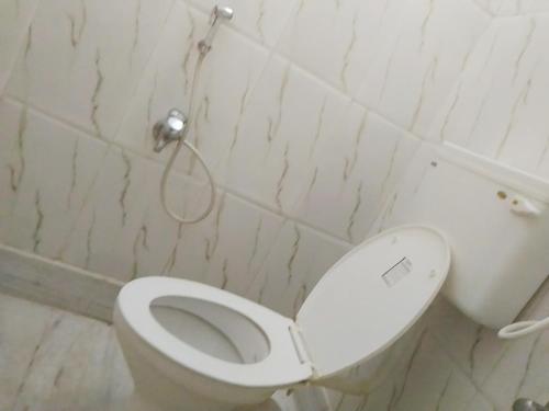 a bathroom with a toilet with the lid up at NIRMAN HOMESTAY 5 minutes walk to beach in Puri