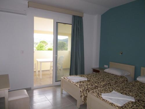 a hotel room with two beds and a balcony at Christakis in Sidari