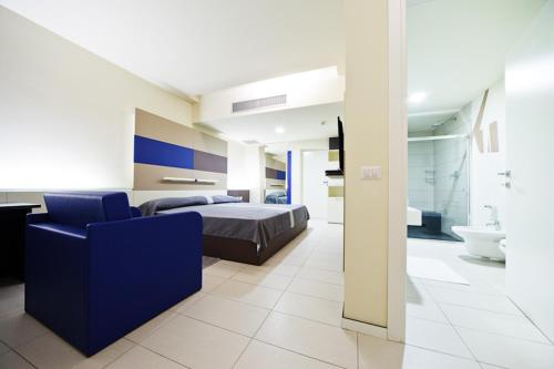 a bedroom with a bed and a blue chair and a bathroom at Motel Autosole Vip in Castelnuovo Scrivia