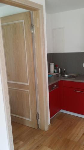 an open door to a kitchen with red cabinets at Ferienwohnung am Meer in Scharbeutz