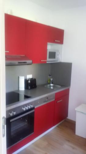 a kitchen with red cabinets and a stove and a sink at Ferienwohnung am Meer in Scharbeutz