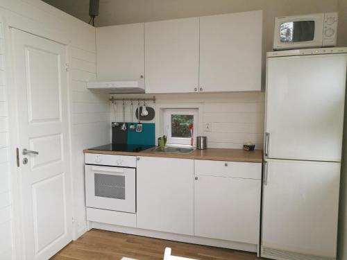 a kitchen with white cabinets and a white refrigerator at Åsarna Hills Holiday Home Stillingsön in Stillingsön