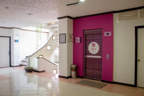 a lobby with a purple wall and a door at Mia City Villahermosa in Villahermosa