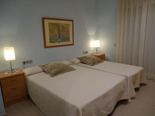 a bedroom with a large white bed with two lamps at Casa Laure y Mª José in Arens de Lledó