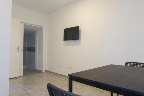 a dining room with a table and a television on a wall at Bonjoia Apartments in Porto