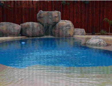 a large swimming pool with a waterfall in a zoo at Kronenhoff Guesthouse in Kirkwood