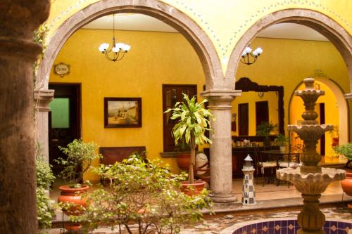 a courtyard with a yellow building with arches and plants at Hotel Casa Dulce Maria in Tequila