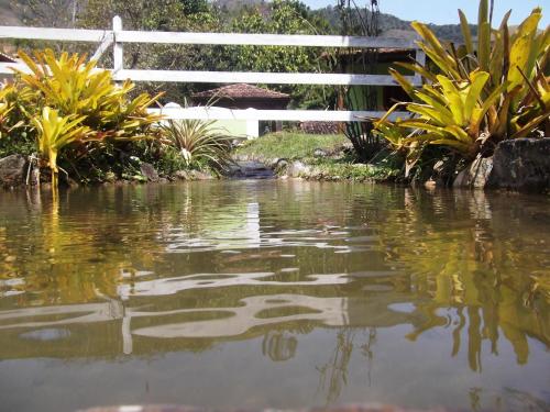 a pond with a white fence and some plants at Rancho Pôr Do Sol in Arapeí