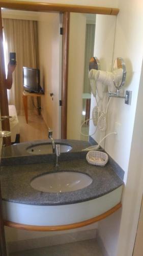 a bathroom with a sink and a mirror at Apart Hotel Quartier Latin in Vitória