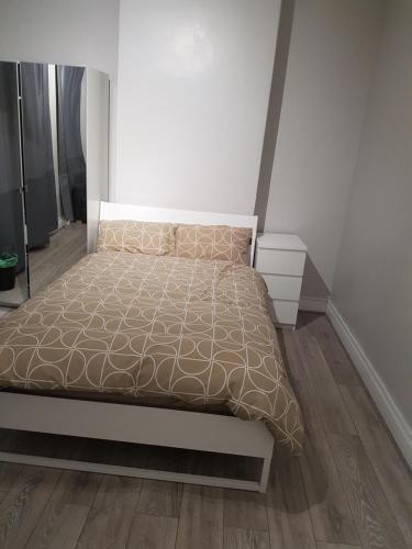 a white bedroom with a bed and a wooden floor at Court Road House in Cardiff