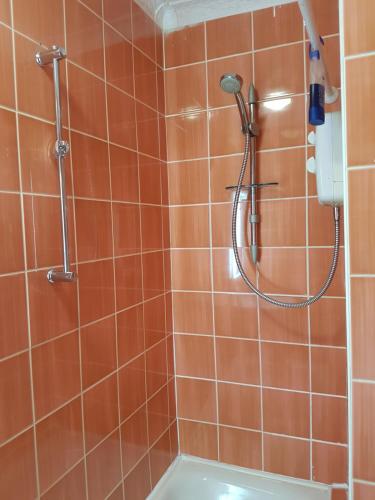 y baño con ducha y azulejos de color naranja. en Court Road House en Cardiff