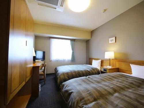 a hotel room with two beds and a television at Hotel Route-Inn Aomori Ekimae in Aomori