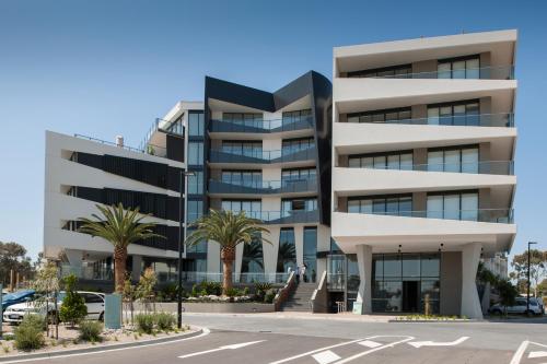 a building with palm trees in front of a parking lot at Caroline Serviced Apartments Sandringham in Sandringham