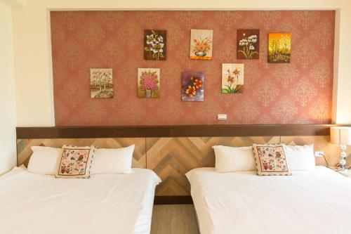 two beds in a room with paintings on the wall at Sky Bird Garden B&B in Wujie