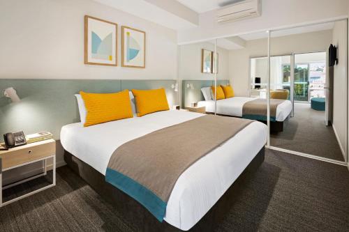 a hotel room with two beds with orange pillows at Quest Eight Mile Plains in Brisbane