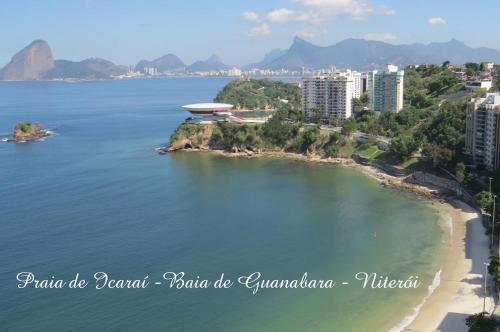 arial view of a beach with a building in the water at Loft Paris in Niterói