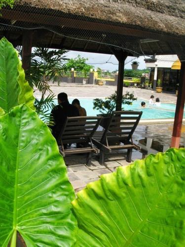 two people sitting on a bench next to a pool at Good Hope Hotel in Skudai