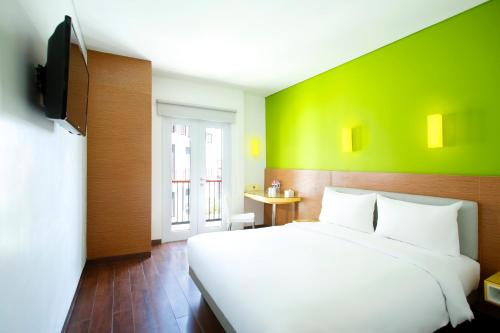 a bedroom with a white bed and a green wall at Amaris Hotel Teuku Umar in Denpasar