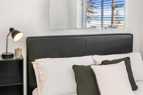 a bed with a black headboard and white pillows at Beachfront on Golden Mile in Sydney