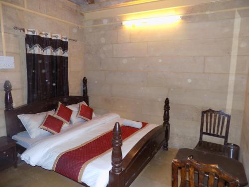 a bedroom with a bed and a chair at Hotel Fotiya jaisalmer in Jaisalmer