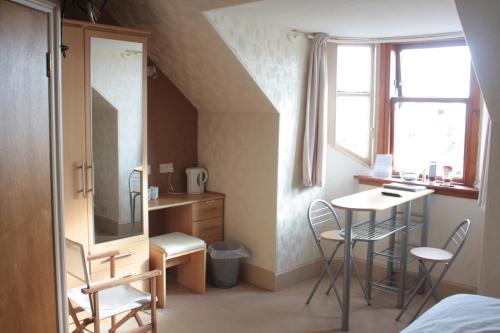 1 dormitorio con escritorio, mesa y sillas en Harbour House Bed & Breakfast - Wick en Wick