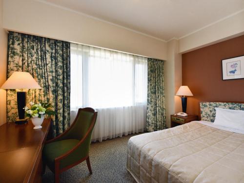 a hotel room with a bed and a desk and a window at Hotel Crown Palais Chiryu in Chiryu