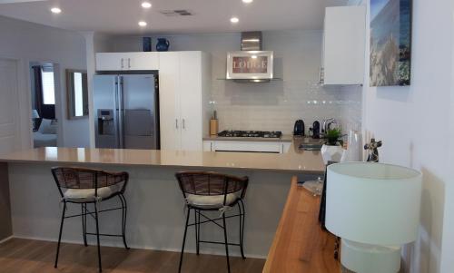 a kitchen with a counter and two bar stools at Carpe Diem South in Busselton