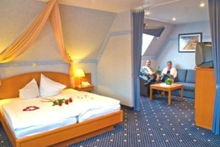 a hotel room with a bed and a tv and two people at Zur Linde in Heede