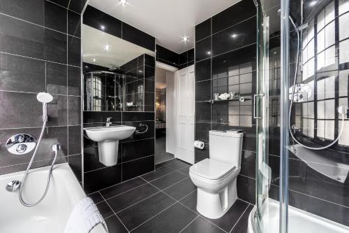 a black bathroom with a toilet and a sink at Muthu Westcliff Hotel (Near London Southend Airport) in Southend-on-Sea