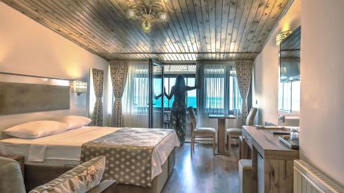 a hotel room with a bed and a woman looking out the window at Akcakoca Poyraz Otel in Akçakoca