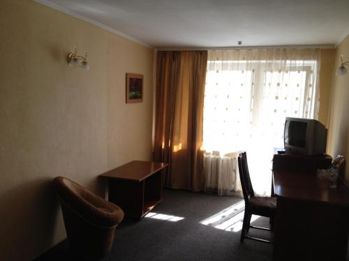 a room with a tv and a table and a window at Tsentralniy Hotel in Khmelʼnytsʼkyy