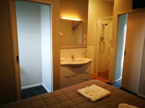 a bathroom with a bed and a sink and a shower at Airport Birches Motel in Christchurch