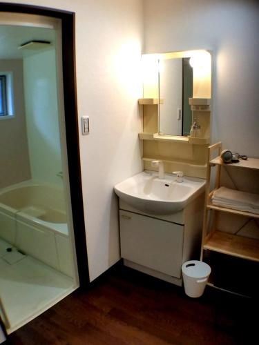 a bathroom with a sink and a toilet and a mirror at Tsudoh Stay Hikoso in Kanazawa