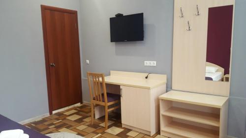 a room with a desk and a television on the wall at Hotel Vega in Krasnodar