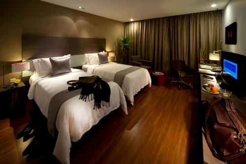 a hotel room with two beds and a television at Pullman Kuching in Kuching