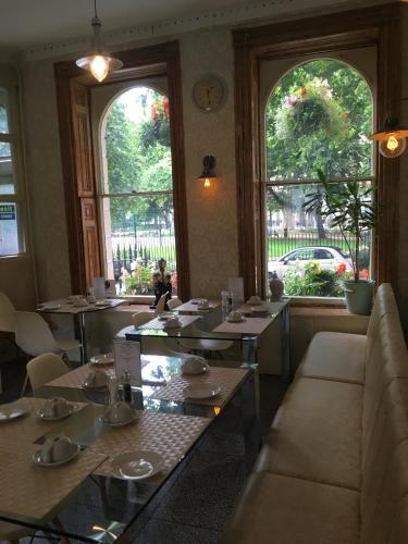 un ristorante con tavoli e sedie e due finestre di George Hotel a Londra